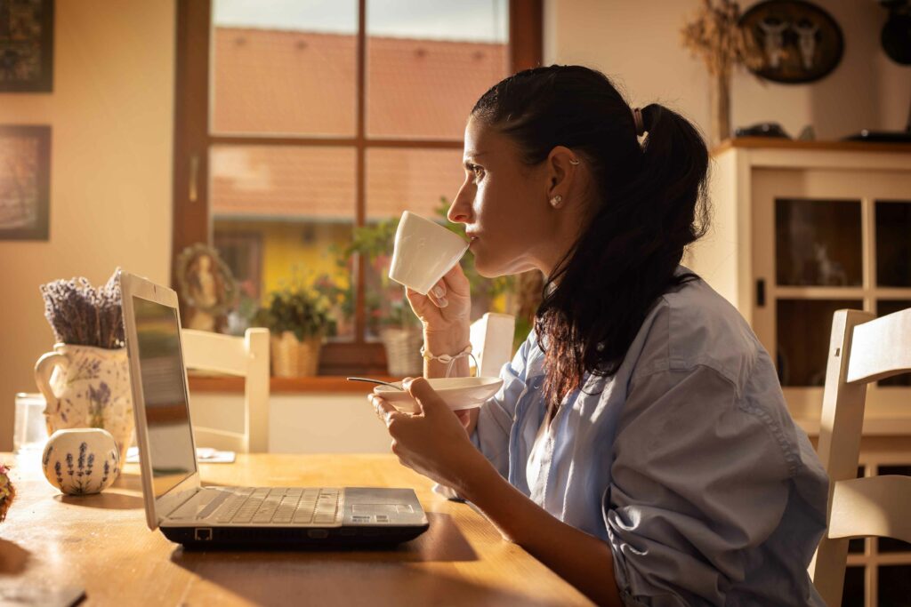 Žena pije kávu při focení brand, které je zaměřeno na home office.