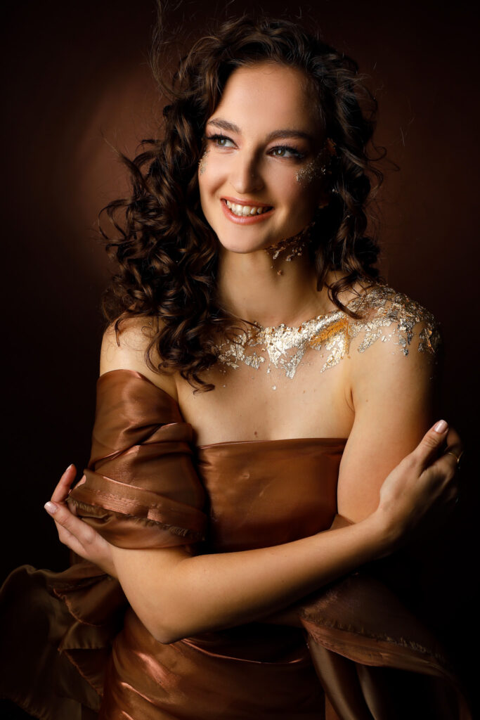 Kreativní fotografie zlata. Zlatý make-up efekt na hnědém pozadí.